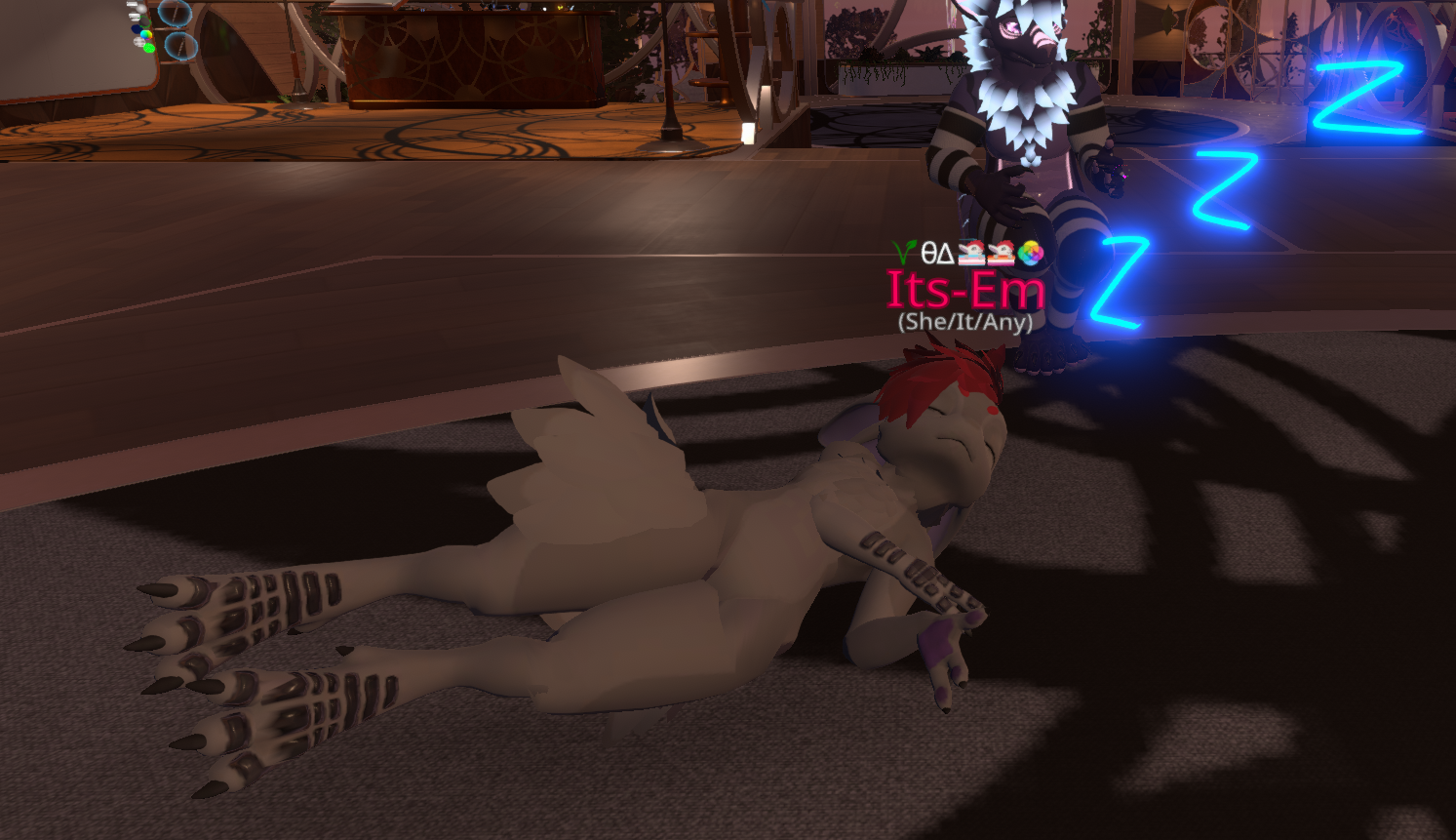 A screenshot of Em asleep on a floor, eyes closed. A friend visible in the background has drawn neon blue Zs above her head.